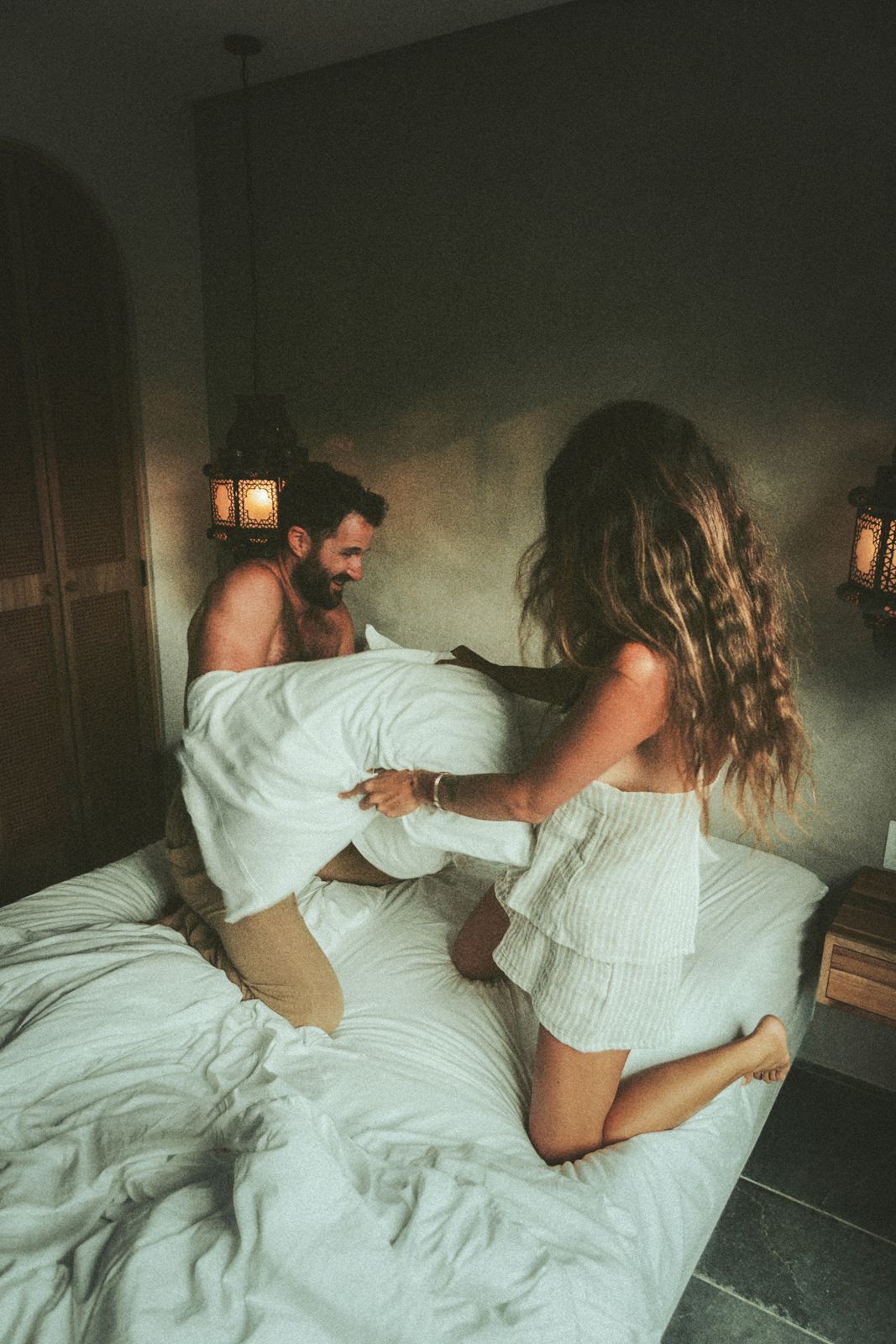 Kyle and his partner laughing in a pillow fight on the bed