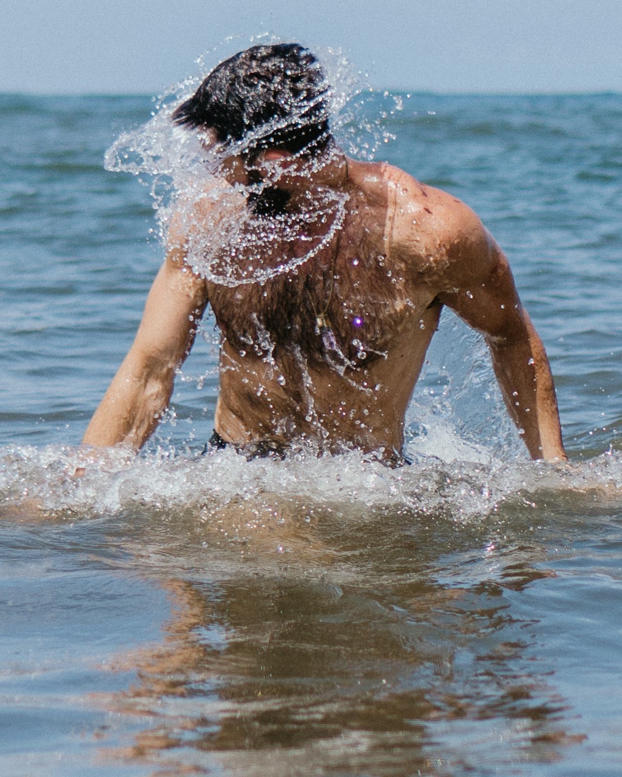 Kyle flicking his hair back as he rises out of the ocean